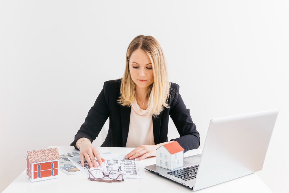 A businesswoman sitting in front of a laptop is looking at the blueprint for minimizing losses.