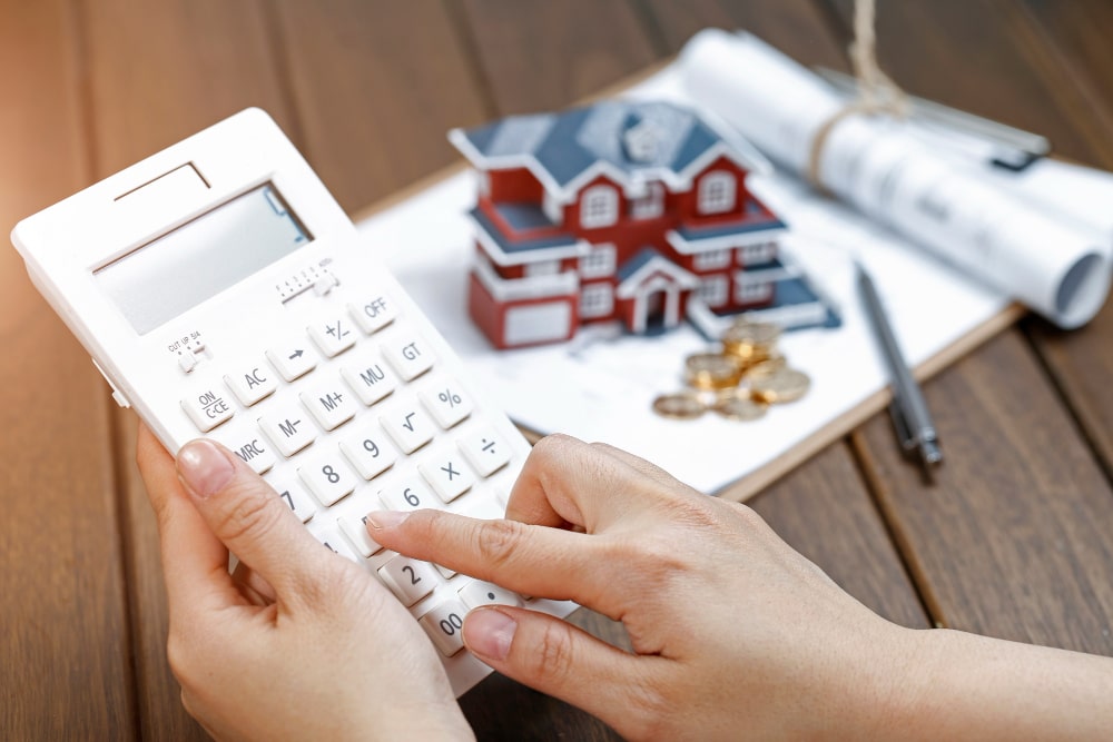 A woman calculates the value of a house on a calculator.